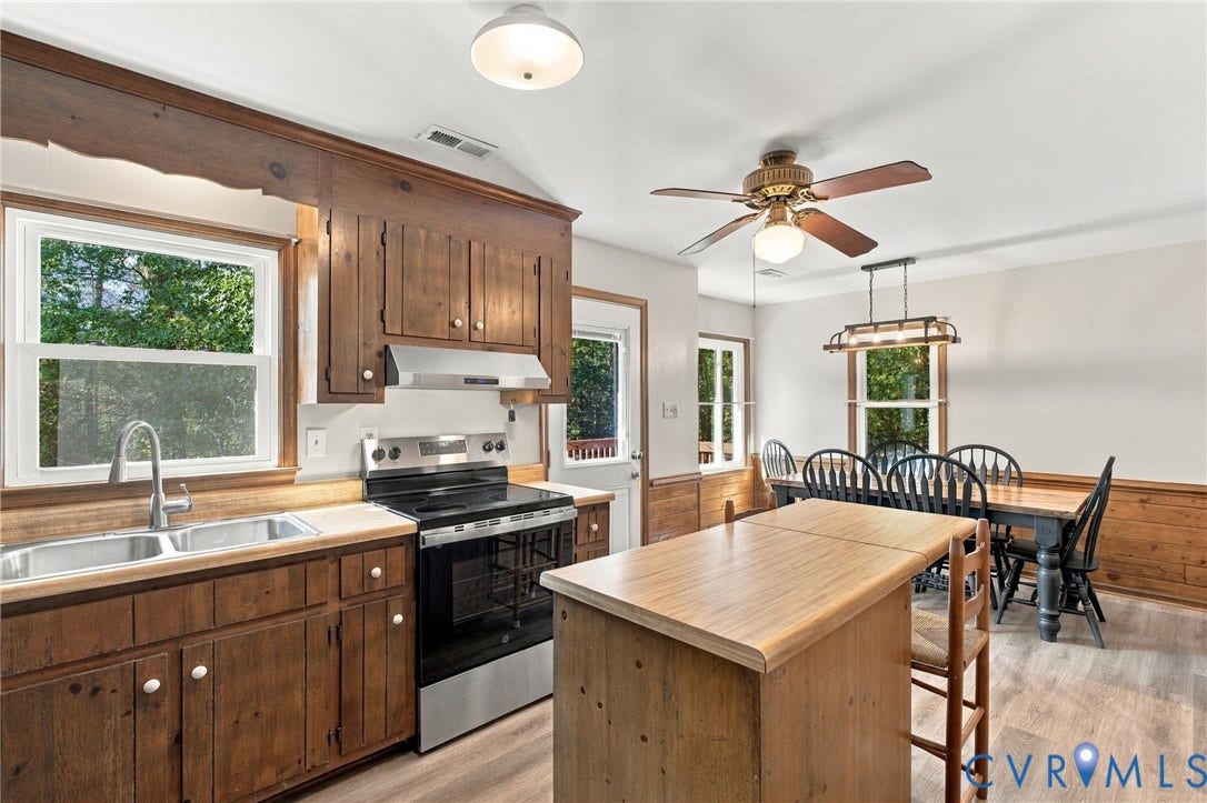 Kitchen featuring stained wood cabinetry, wood-finish flooring, a stainless steel range with a matching range hood, and a built-in kitchen island