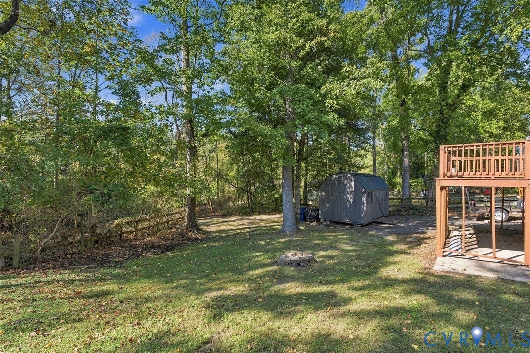 Expansive backyard featuring a wood-rail perimeter fence, multi-level deck, detached storage structure, and mature trees