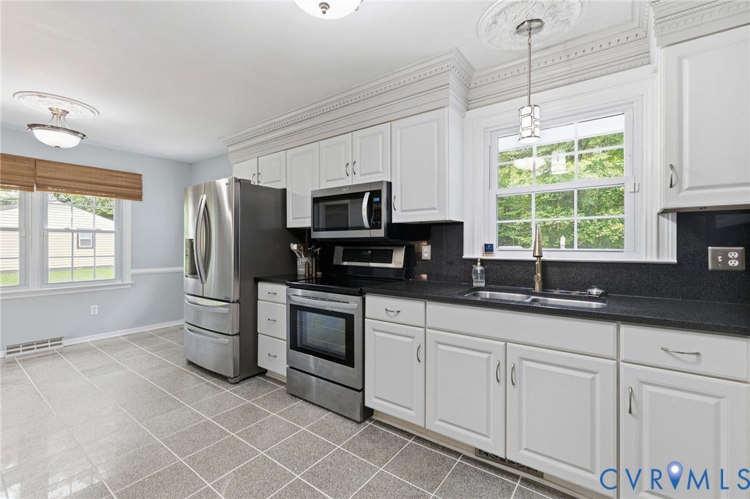 6723 Cherry Road, Woodhaven Shores, Quinton, VA 23141 White cabinetry, stainless steel appliances, dark countertops, tiled flooring, and crown molding