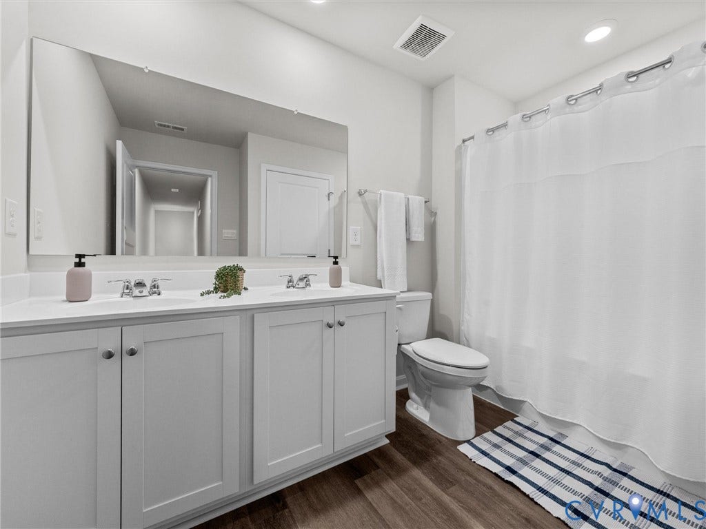 6901 Switch Cane Court, The Arbors, New Kent, VA 23141 Dual vanity with individual sinks, expansive mirror, wood-finish flooring, and recessed ceiling lighting