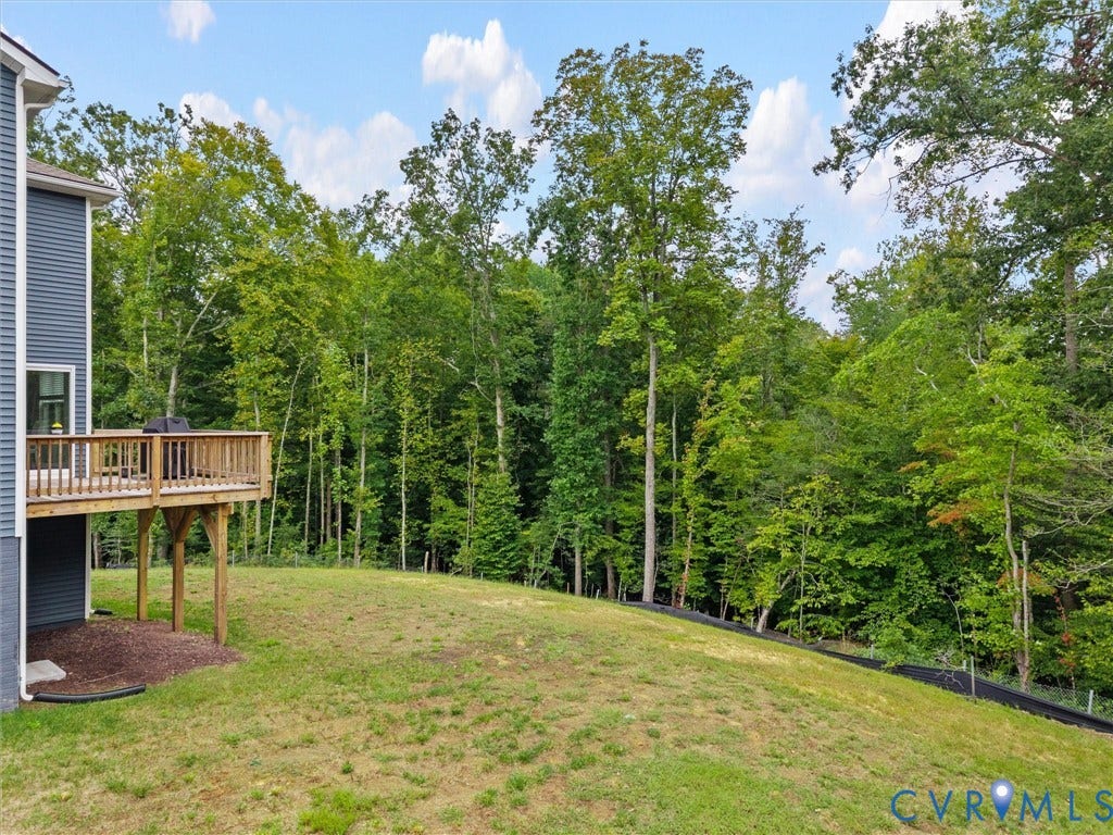 6901 Switch Cane Court, The Arbors, New Kent, VA 23141 Expansive backyard with a wooden deck, sloped lawn, and mature trees bordering the property