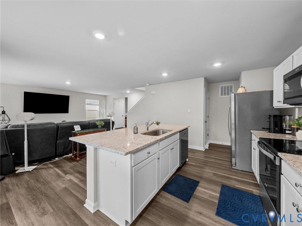 6901 Switch Cane Court, The Arbors, New Kent, VA 23141 Kitchen island with built-in sink and dishwasher, white cabinetry, integrated stainless steel appliances, and wood-finish flooring