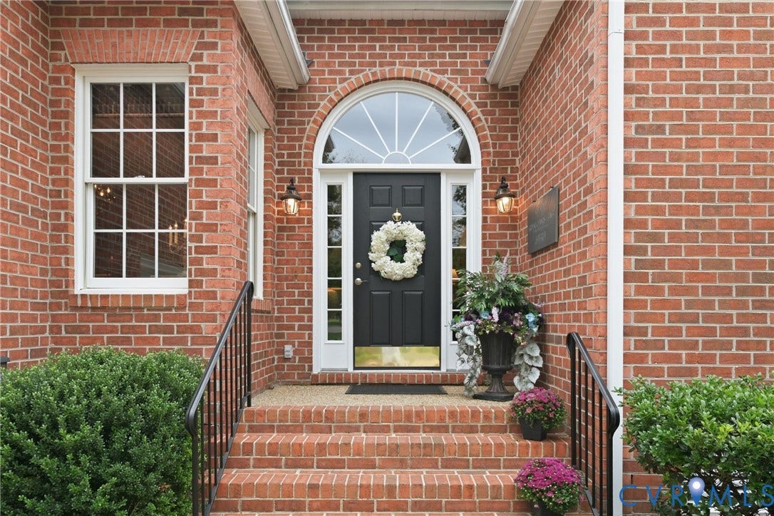 Brick facade with arched transom window, a black front door, and a brick-built porch with steps