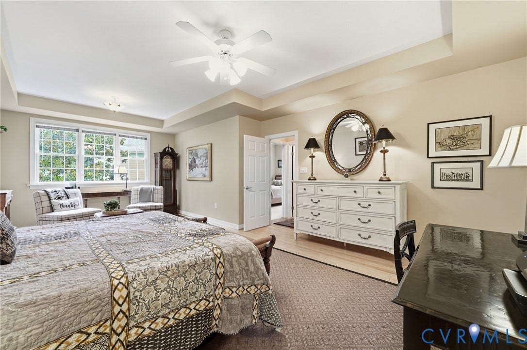 Tray ceiling, recessed lighting, ceiling fan, large multi-pane window, and a paneled interior door