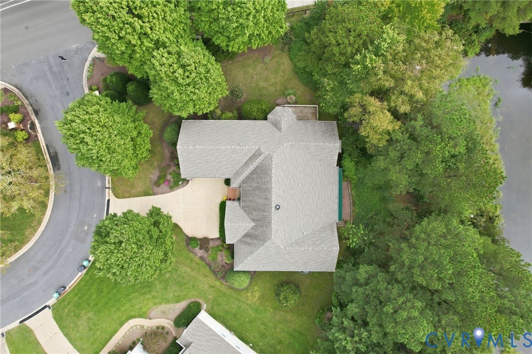 Expansive property with mature trees, a driveway, and a shingle roof