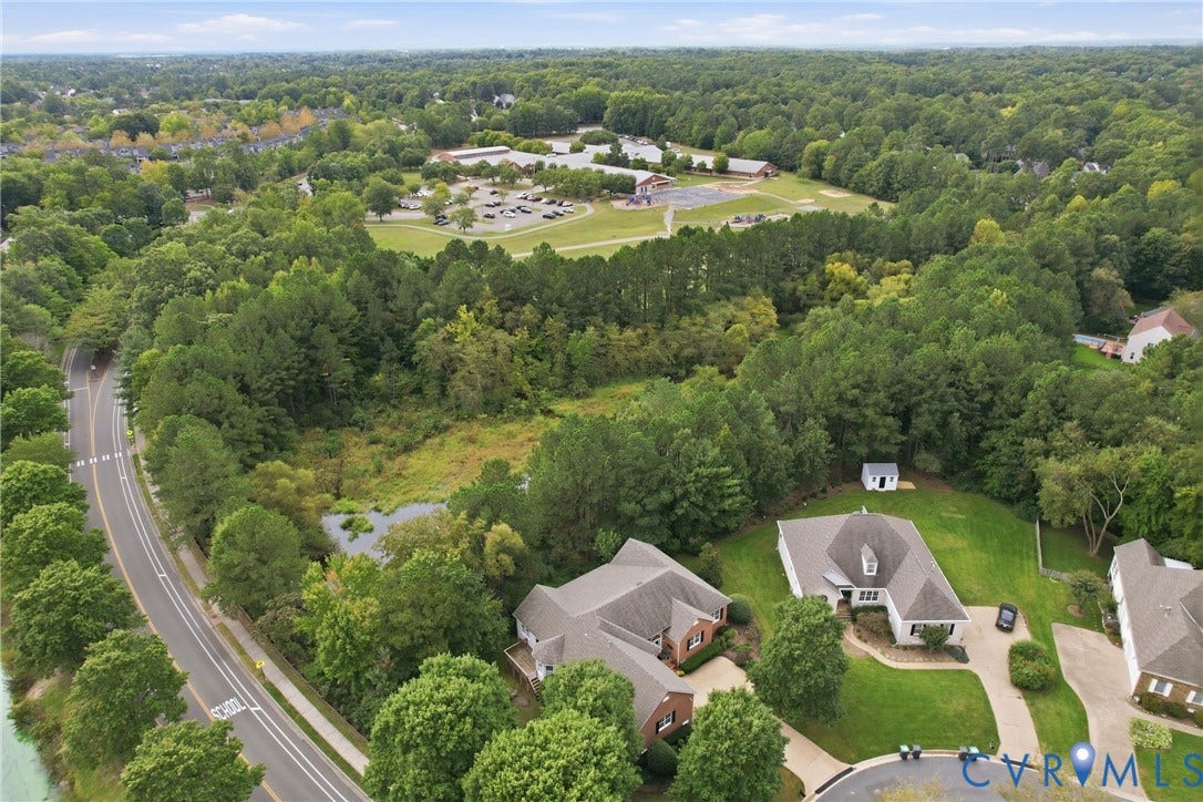 Aerial perspective showcasing a residential area with mature trees, a paved road, and a circular drive