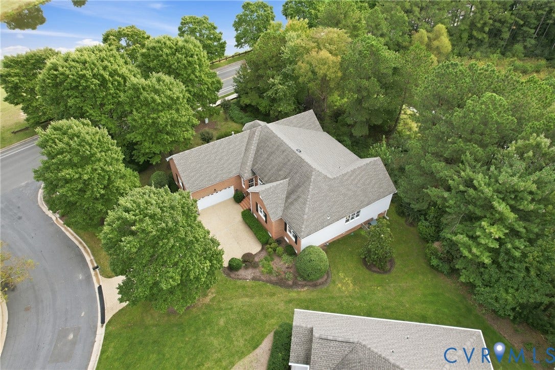 Red brick exterior, multi-gabled roofline, two-car garage, mature trees, and an asphalt driveway