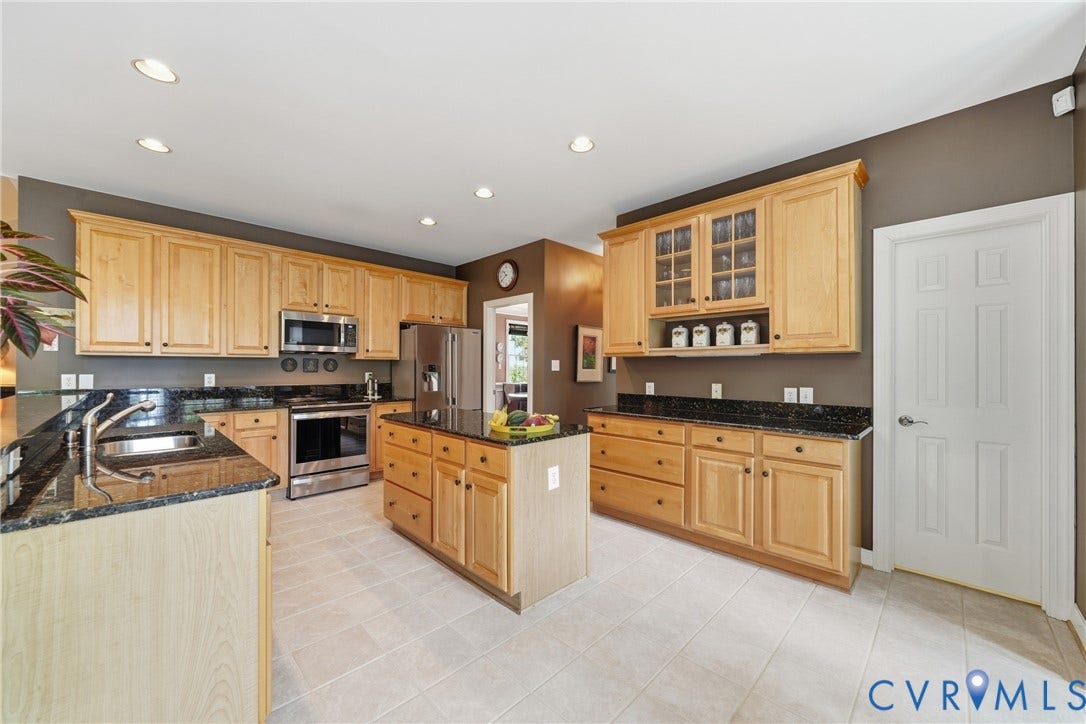 Kitchen featuring natural wood cabinetry, dark stone countertops, stainless steel appliances, a center island, and recessed lighting