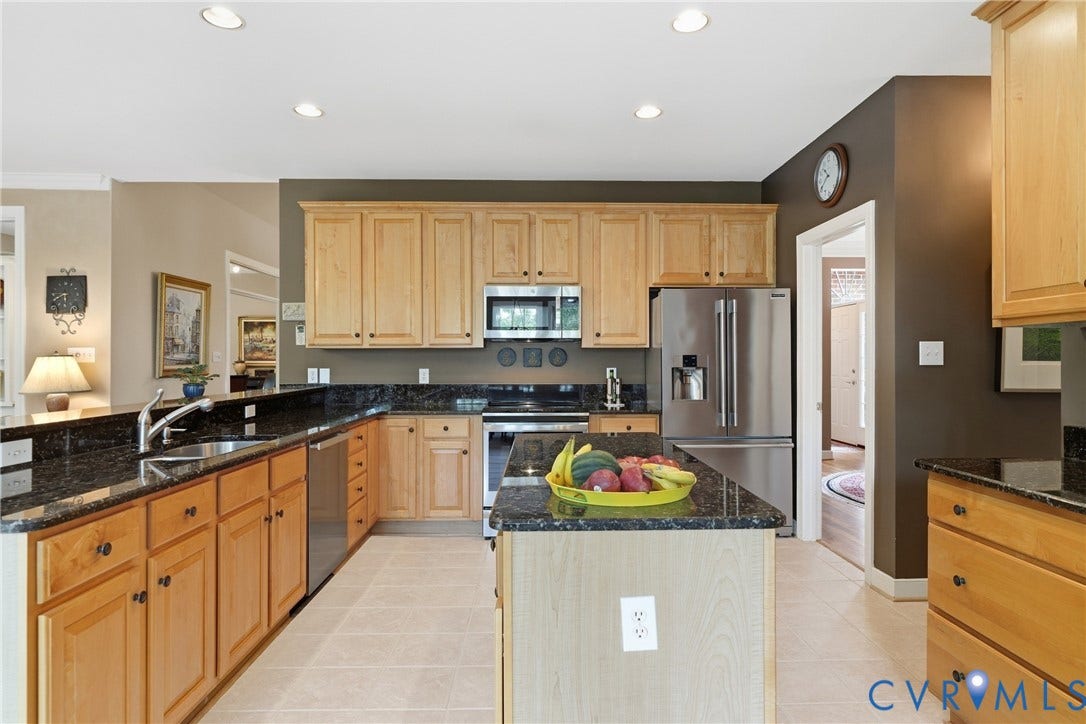 Kitchen featuring wood cabinetry, dark stone countertops, stainless steel appliances, a center island, and recessed lighting
