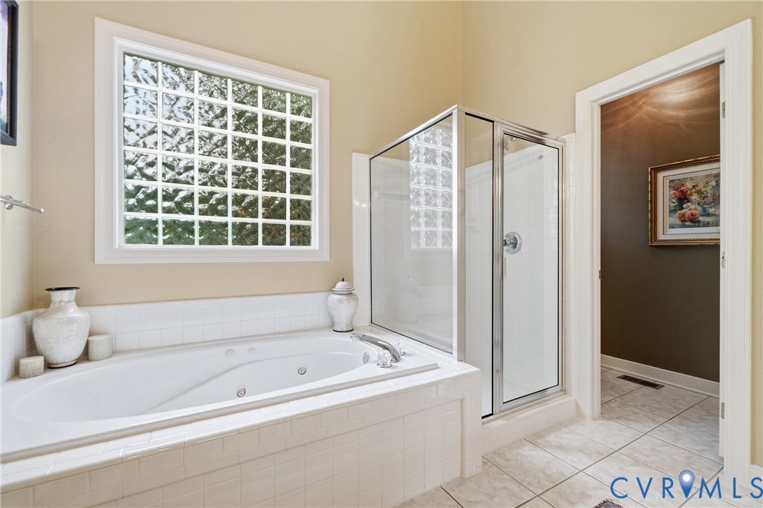 Built-in jetted tub with tiled surround, glass block window, and adjacent glass-enclosed shower