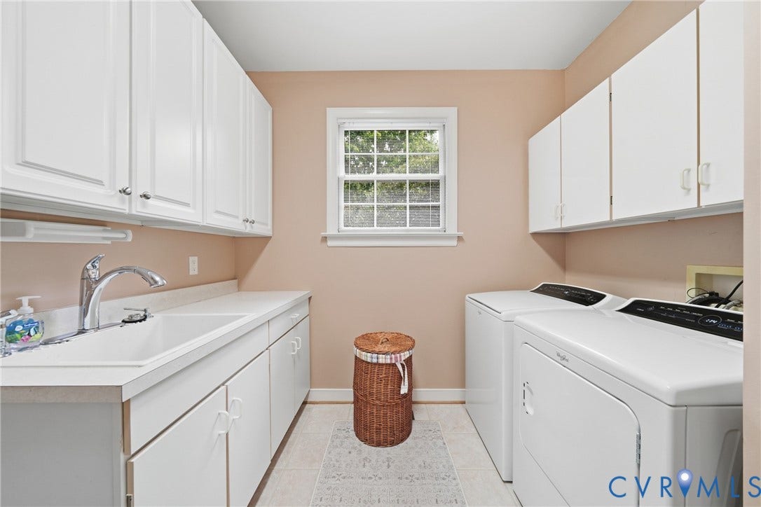 Utility sink with a chrome faucet, white cabinetry, a large window, and tile flooring