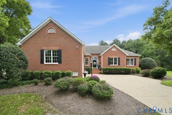 Brick facade residence with a gabled roofline, arched front entry, and a paved driveway