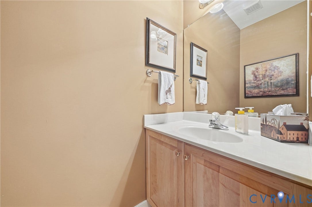 Single vanity with a light wood-finish cabinet and a white countertop