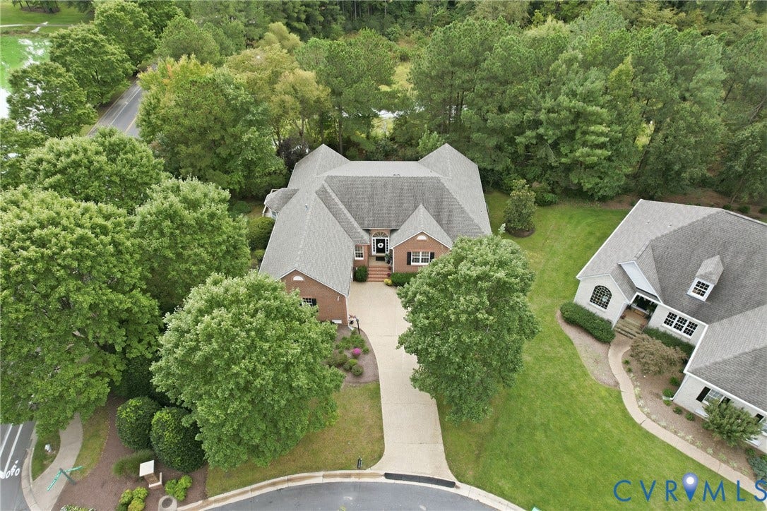 Brick exterior, multi-gabled roofline, mature trees, landscaped front yard, paved driveway