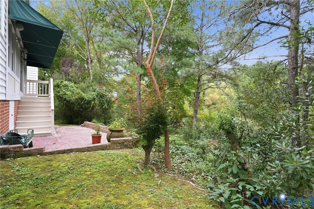 Expansive outdoor space featuring a brick patio, steps with railings, and mature trees