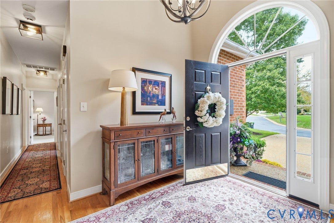 Arched transom window above a panel entry door with sidelights, wood-finish flooring, and a hallway with recessed lighting