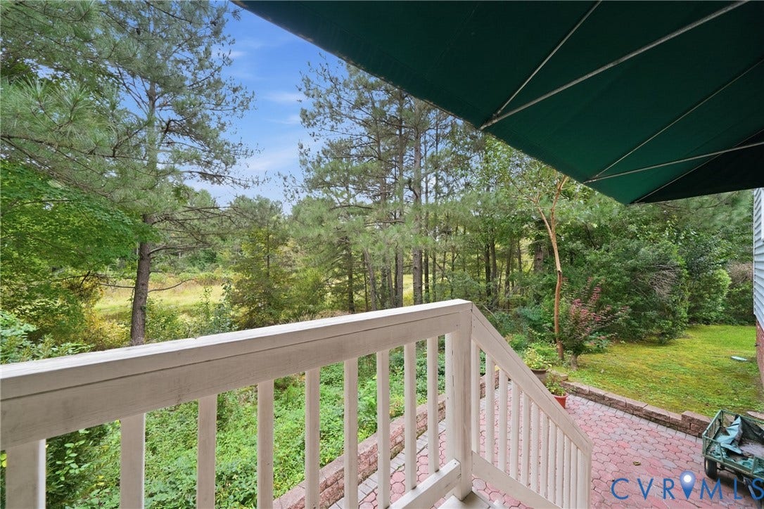 Covered patio with a brick paver surface, white railing, and a green retractable awning