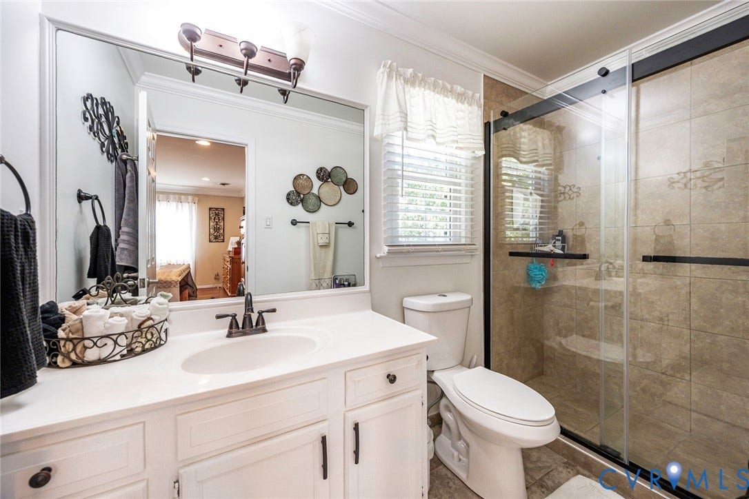 White vanity with integrated sink, bronze-finish faucet, and a large wall-mounted mirror