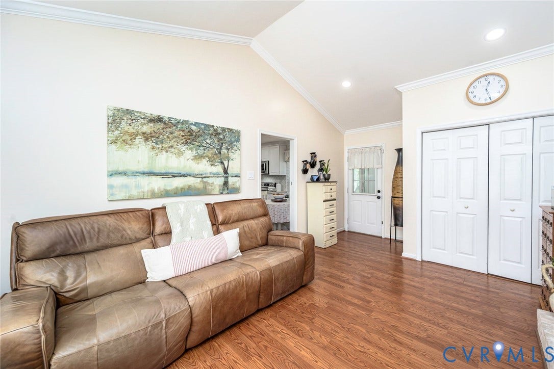 Vaulted ceiling, crown molding, wood-finish flooring, recessed lighting, and white bi-fold doors