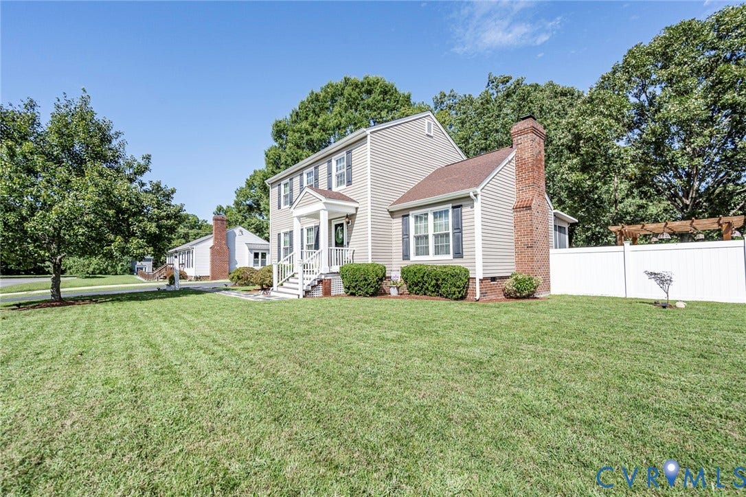 Siding exterior with brick chimney, white picket fence, and extensive lawn