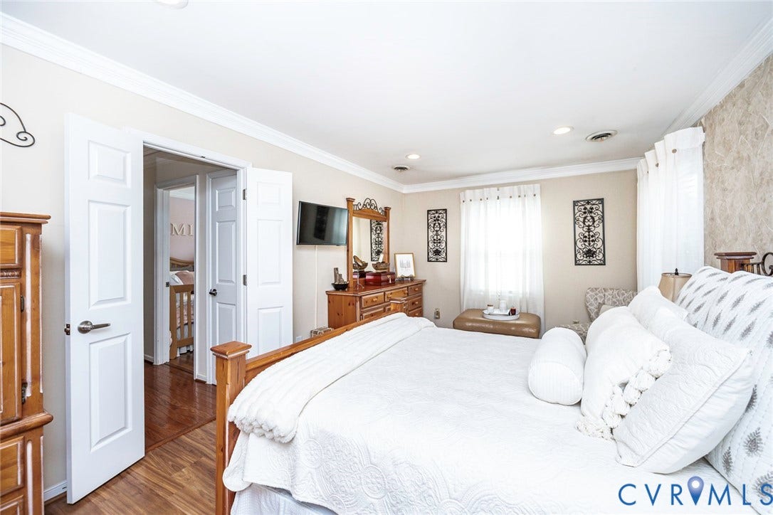 Recessed lighting, crown molding, wood-finish flooring, white paneled doors, and a decorative accent wall