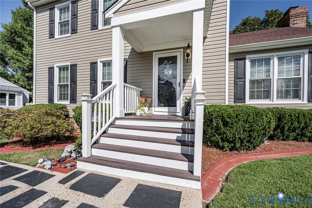 Front entrance with covered porch, white railings, and dark-stained steps