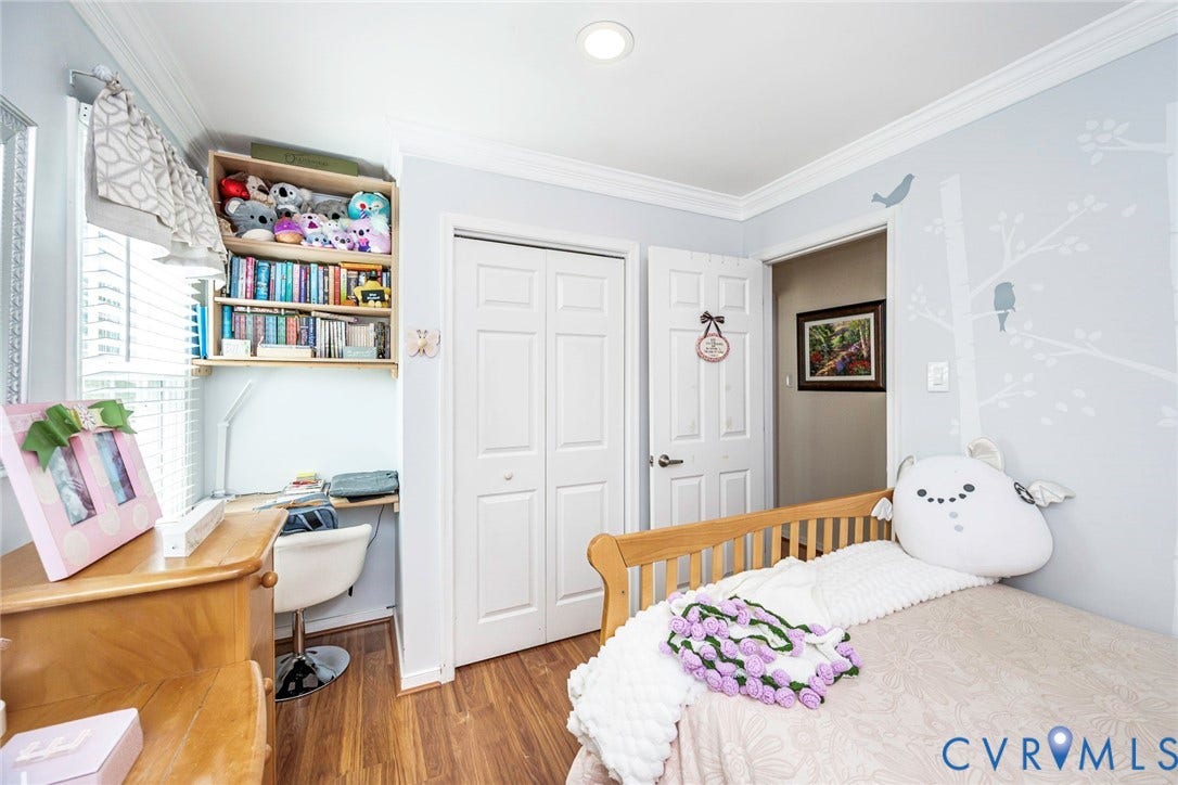 Recessed ceiling lighting, wood-finish flooring, built-in shelving, white bi-fold closet doors, and crown molding