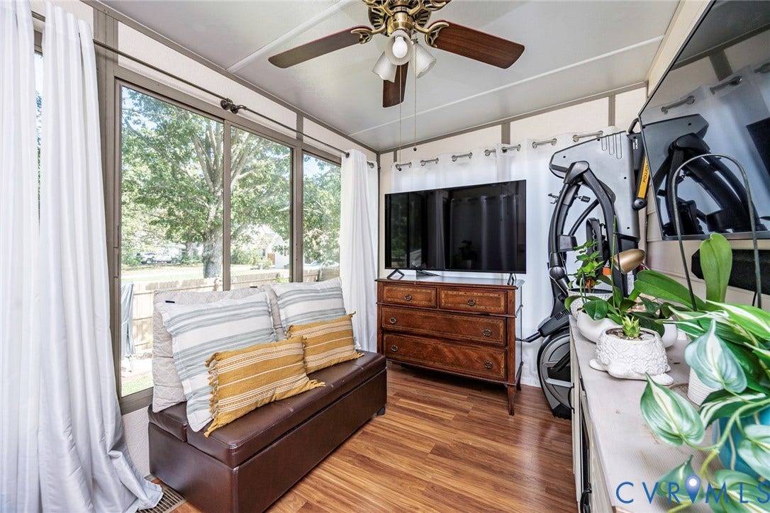 Sunroom with expansive windows, a ceiling fan, and wood-finish flooring