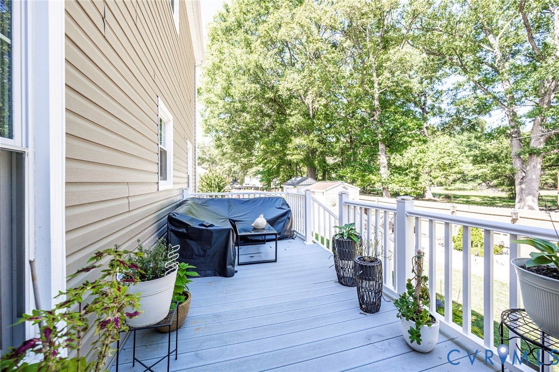 Outdoor deck with white railings, light-colored decking, and tan siding