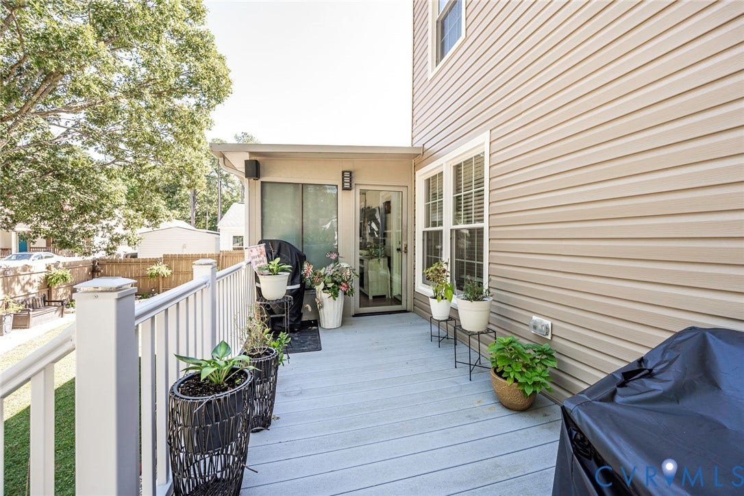 Outdoor deck featuring gray composite decking, white railing with square posts, and tan horizontal siding