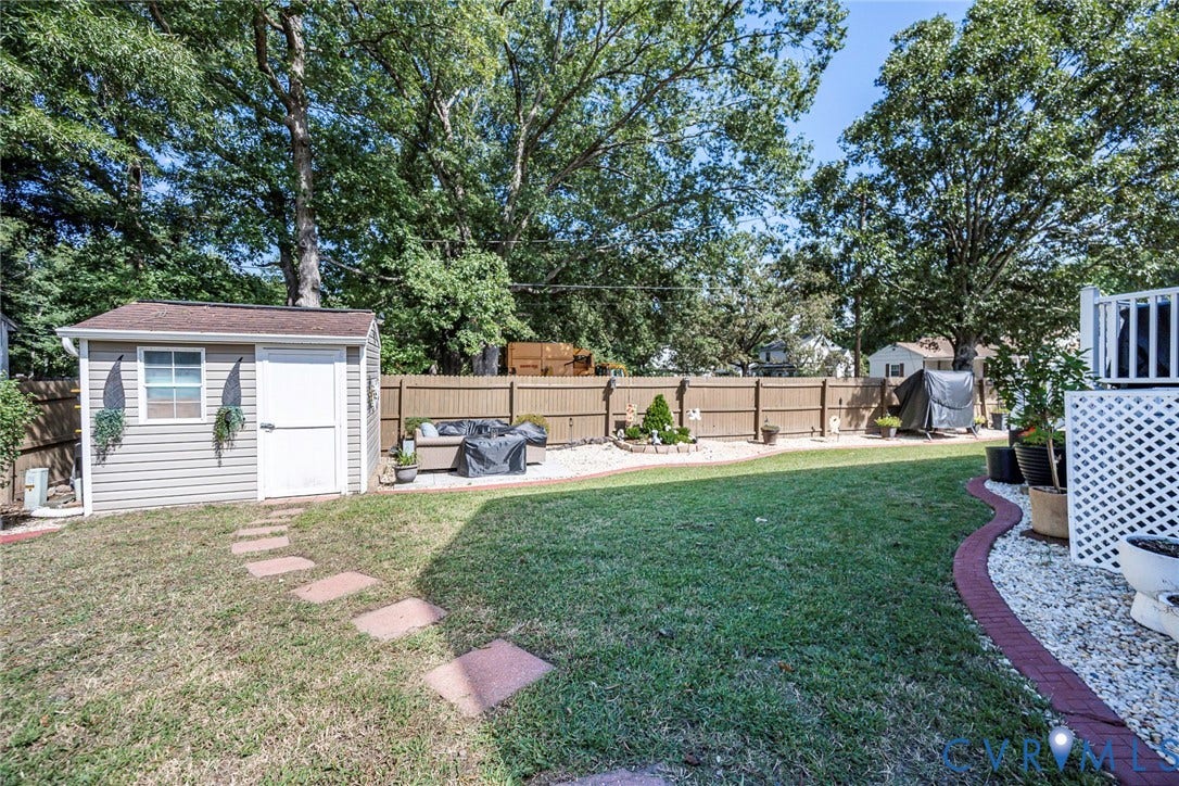 Expansive yard featuring a manicured lawn, a detached storage shed, a wood fence, and a decorative white lattice enclosure