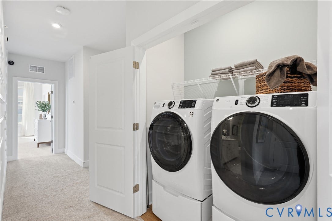 Dedicated laundry area featuring stacked front-loading washer and dryer units