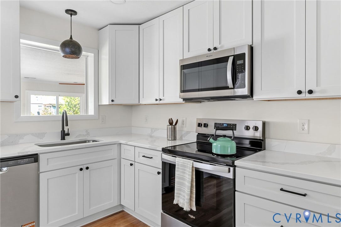7402 Edgewood Avenue, Richmond, VA 23227 White shaker-style cabinetry, stainless steel appliances, quartz countertops with matching backsplash, and wood-finish flooring