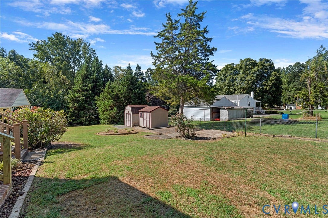 7402 Edgewood Avenue, Richmond, VA 23227 Expansive grassy yard with mature trees, two storage sheds, and a chain-link fence