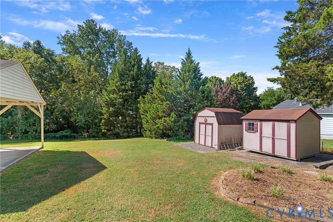 7402 Edgewood Avenue, Richmond, VA 23227 Expansive grassy yard with mature trees, featuring two detached storage sheds and a covered carport
