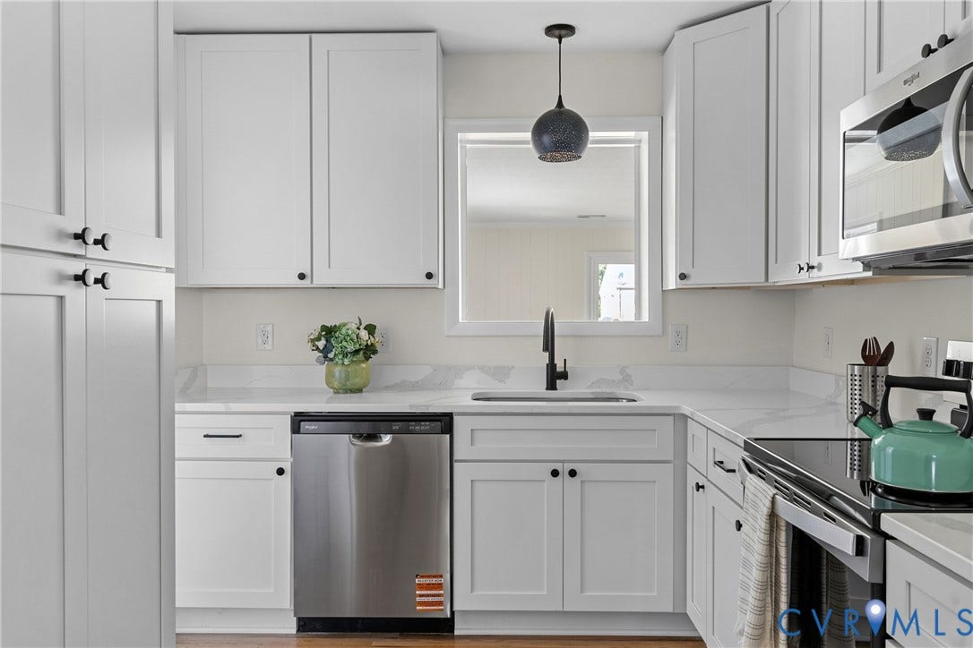 7402 Edgewood Avenue, Richmond, VA 23227 White shaker cabinetry, stainless steel appliances, white countertops, wood-finish flooring, and a modern pendant light fixture