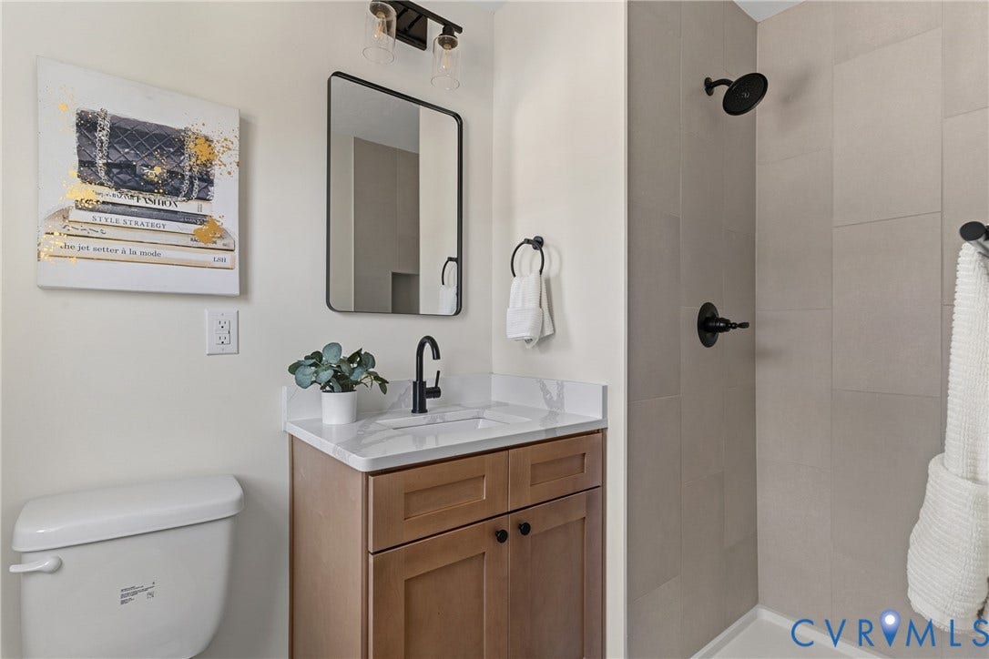 7402 Edgewood Avenue, Richmond, VA 23227 Modern vanity with a white countertop and integrated sink, matte black fixtures, rectangular wall-mounted mirror, and a tiled shower enclosure