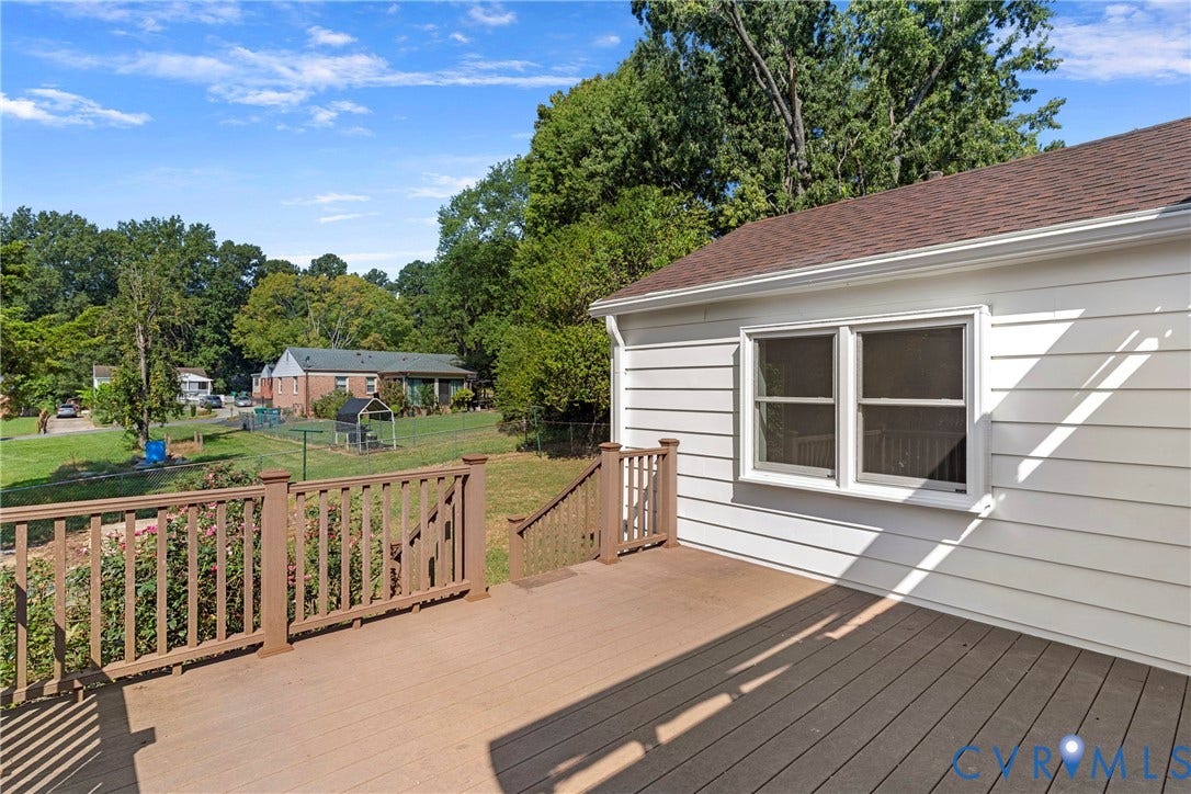 7402 Edgewood Avenue, Richmond, VA 23227 Expansive composite deck with wooden railings, white siding, and a brown shingle roof