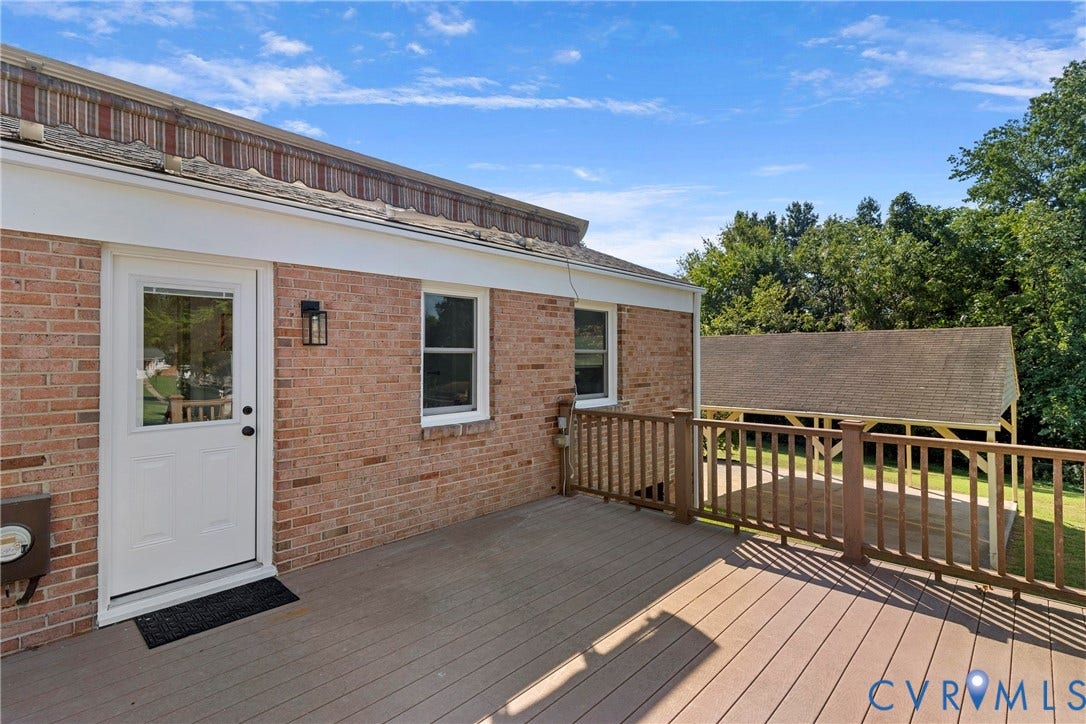 7402 Edgewood Avenue, Richmond, VA 23227 Expansive composite deck with a wood-finish railing, brick exterior, white trim, and an attached carport