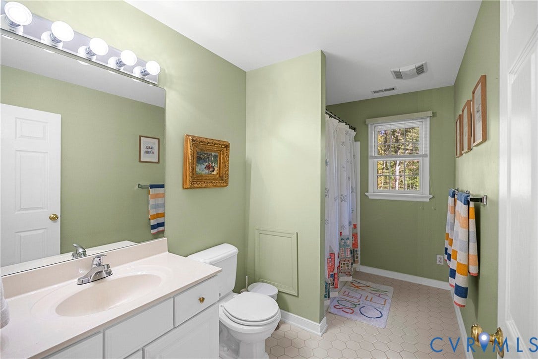 12082 Victoria Hills Road, Rockville, VA 23146 Bathroom featuring a white vanity with an integrated sink, a full-width vanity mirror, multi-bulb wall lighting, a window, and hexagon-patterned tile flooring