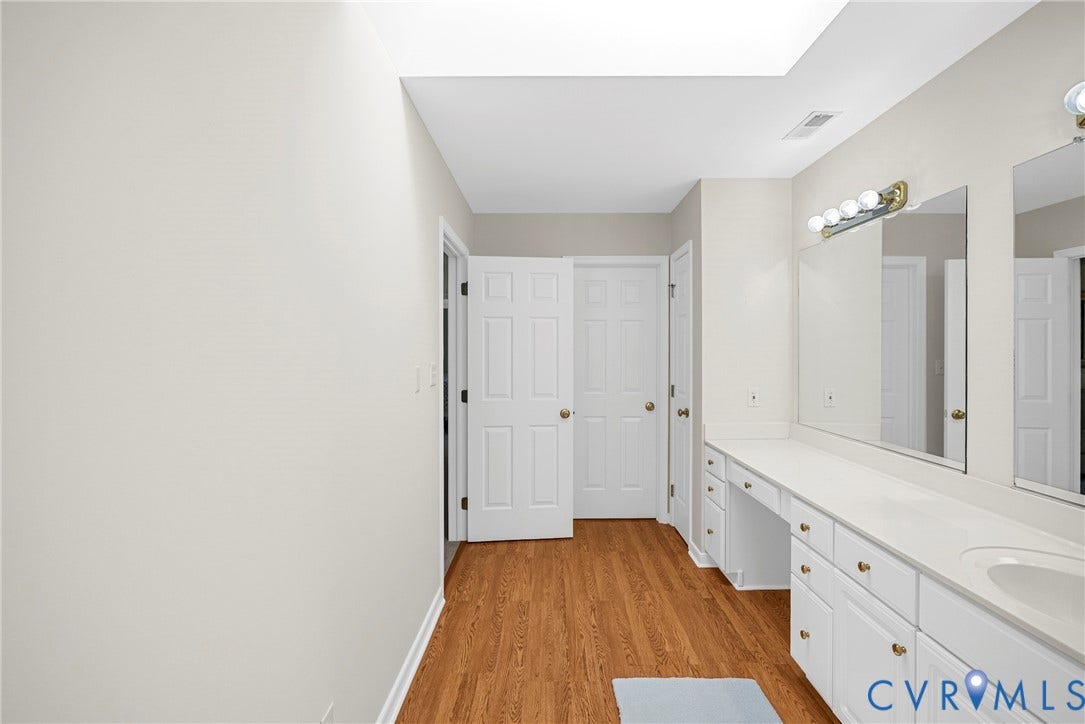 12082 Victoria Hills Road, Rockville, VA 23146 Long vanity with countertop and dual sinks, wood-finish flooring, skylight, and multi-panel doors