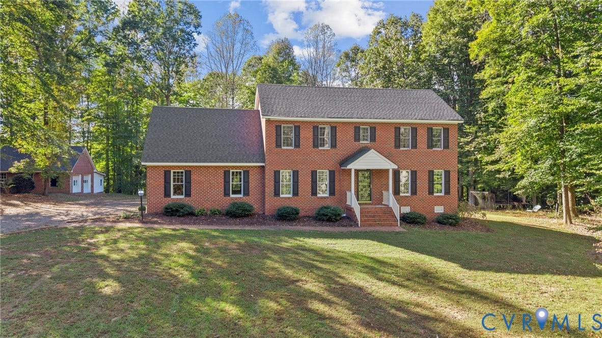 12082 Victoria Hills Road, Rockville, VA 23146 Two-story brick exterior featuring a shingled roof, dark shutters, a covered front entry with white railings, and a multi-car detached garage