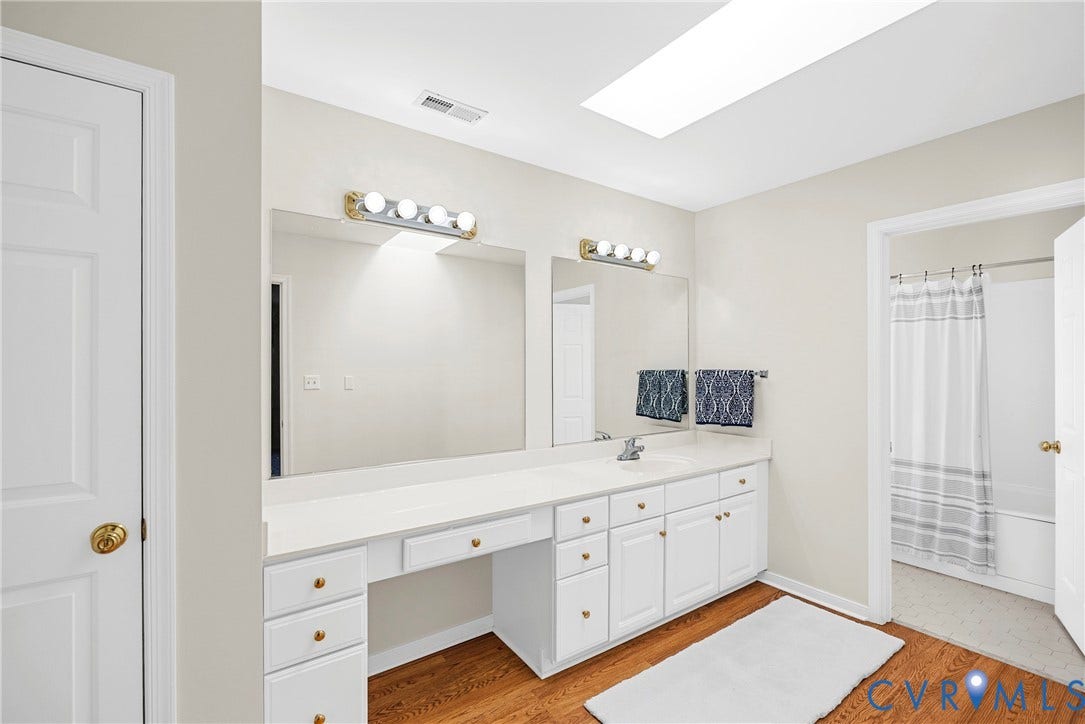 12082 Victoria Hills Road, Rockville, VA 23146 Dual-sink vanity with white cabinetry, light-toned countertop, skylight, and wood-finish flooring