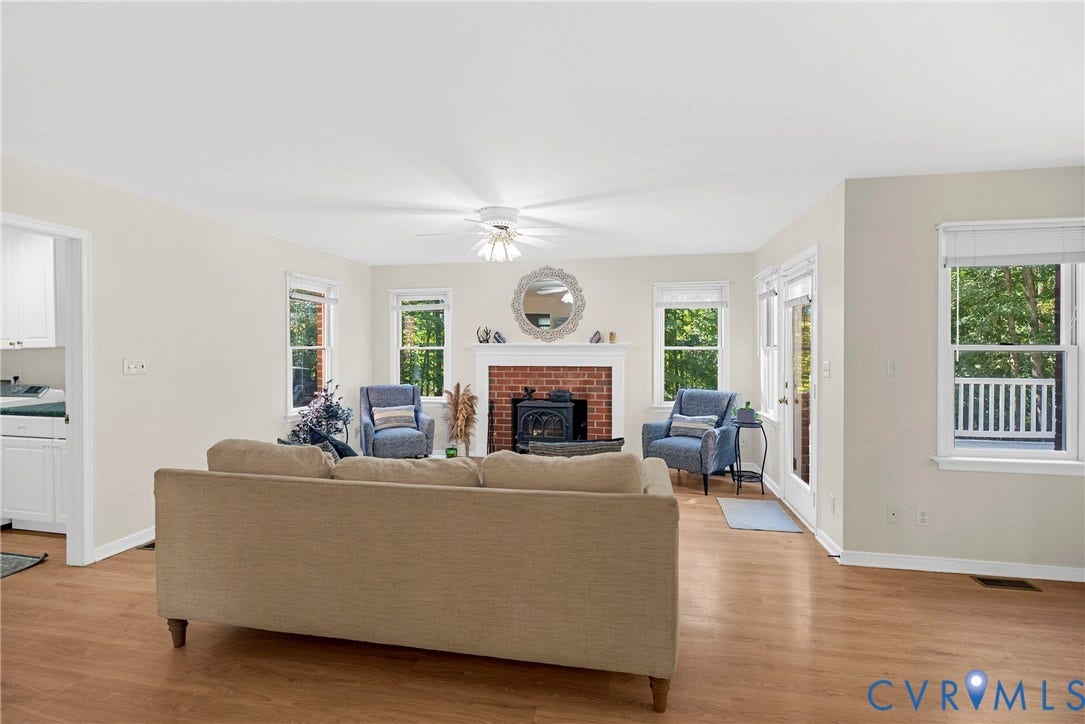 12082 Victoria Hills Road, Rockville, VA 23146 Living space featuring wood-finish flooring, brick fireplace with a wood-burning insert, mantel, multiple windows, and a ceiling fan