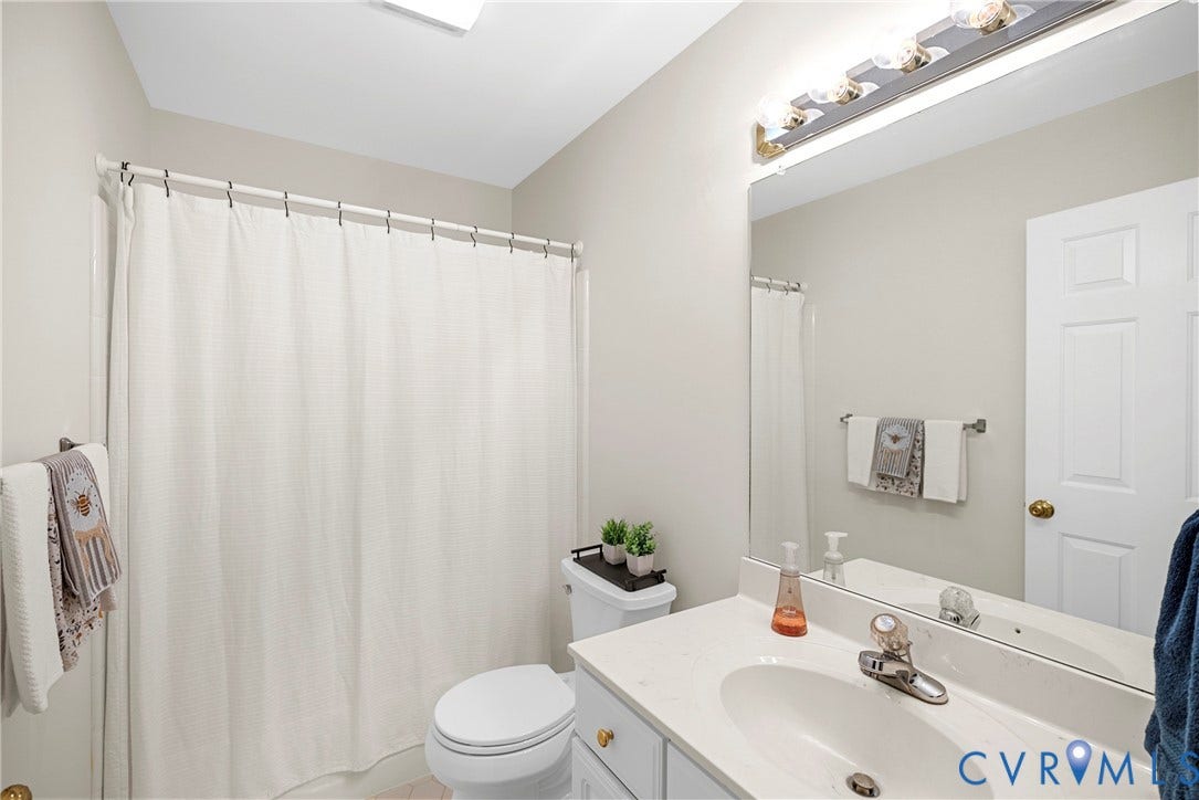 12082 Victoria Hills Road, Rockville, VA 23146 Bathroom featuring a vanity with a light-toned countertop, integrated basin, and brushed-nickel faucet, complemented by a large wall-mounted mirror and multi-bulb vanity lighting