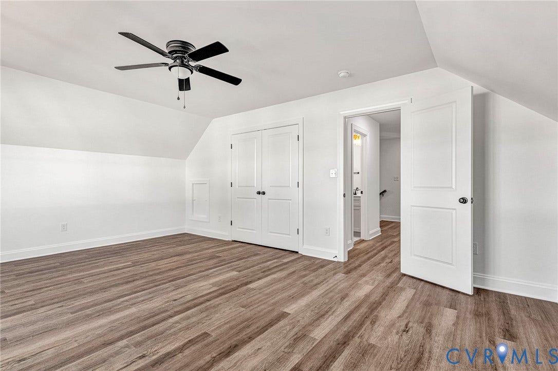 Angled ceiling lines, wood-finish flooring, a ceiling fan, and double-door storage