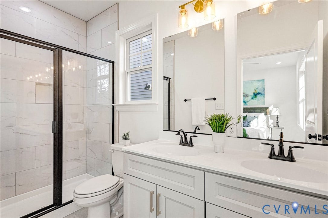 Double vanity with white cabinetry and integrated sinks, matte black fixtures, and a gold-toned light bar