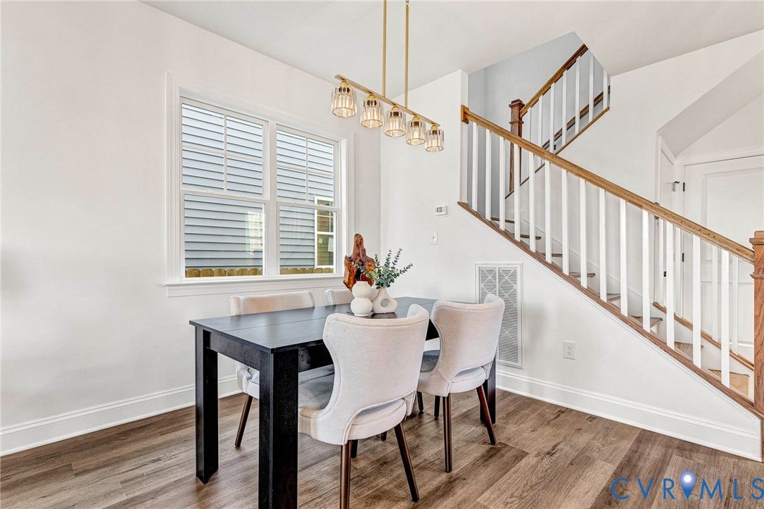 Wood-finish flooring with white baseboards, a dual-pane window, and a staircase featuring wood handrails and white balusters