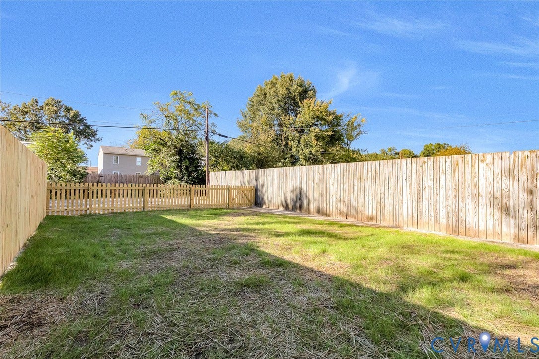Expansive backyard with a wood picket fence and a tall wood privacy fence