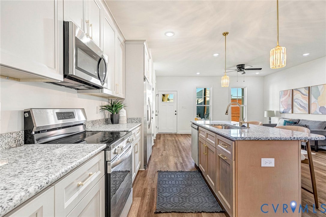 Kitchen featuring an eat-at island with undermount sink, stainless steel appliances, granite countertops, and wood-finish flooring